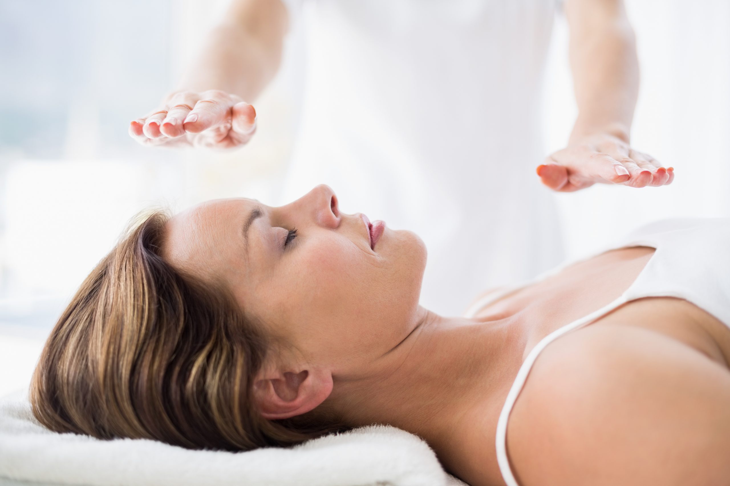 Midsection of therapist performing reiki treatment on woman at spa